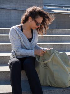 Woman sitting outside wearing a wrap-a-round top in grey melange color. Kvinna sitter utomhus klädd i en gråmelerad omlott top