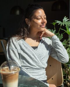 Woman sitting outside wearing a wrap-a-round top in grey melange color. Kvinna sitter utomhus klädd i en gråmelerad omlott top