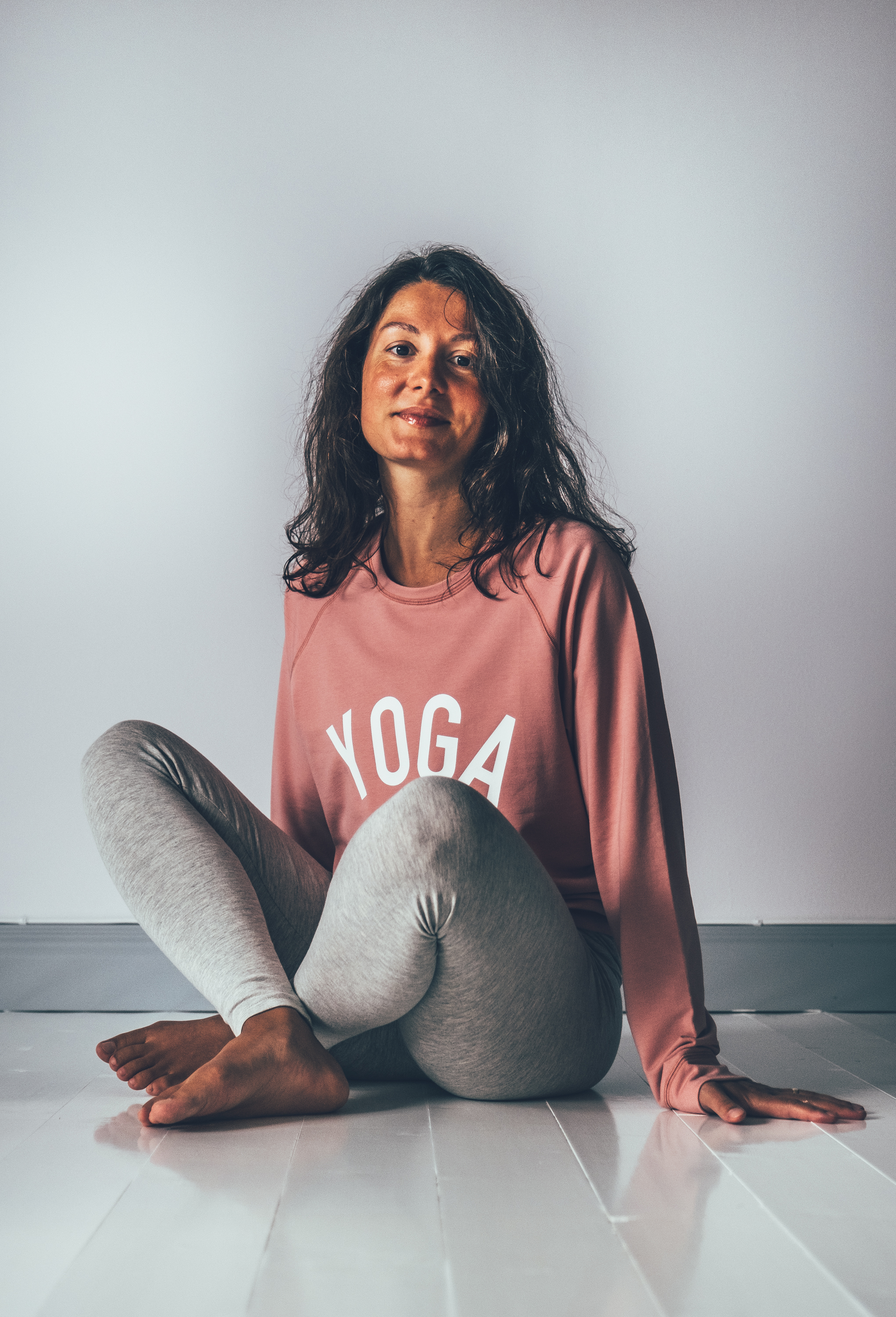 Model wearing a pink yogasweater with the letters YOGA in white.
