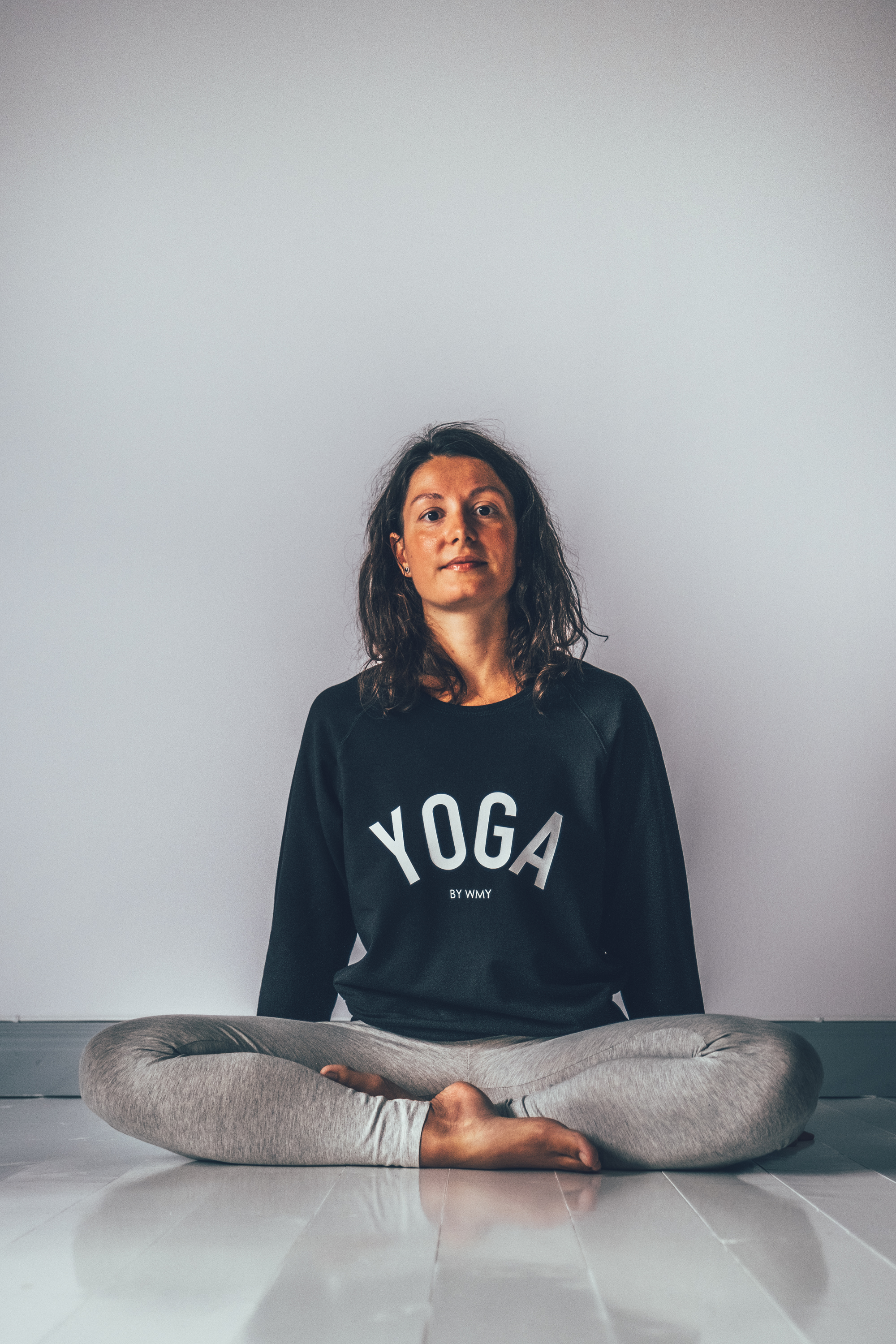 Model wearing a black yogasweater with the letters YOGA in white.