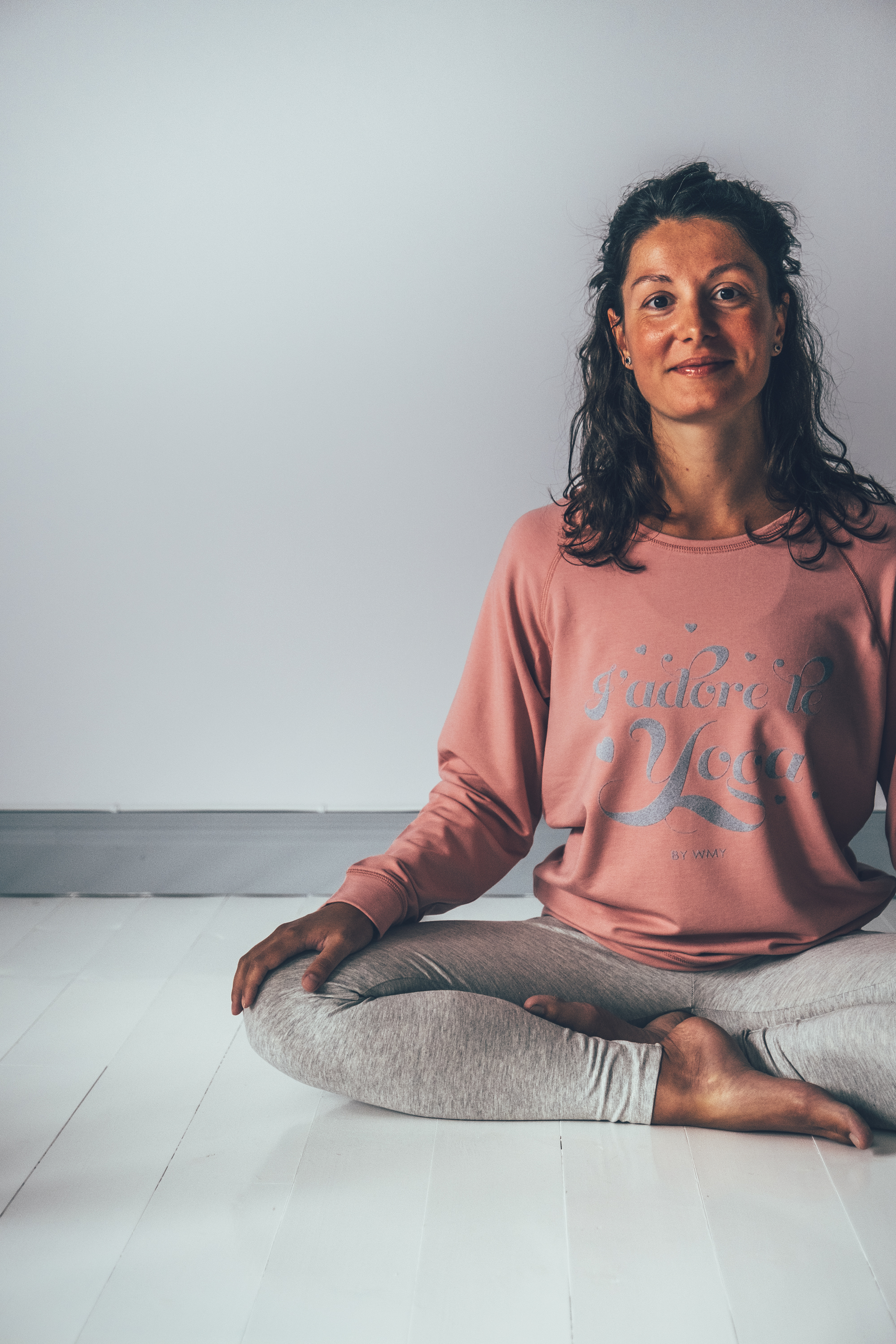 Model wearing a pink yogasweater with the letters I'adore Yoga in grey