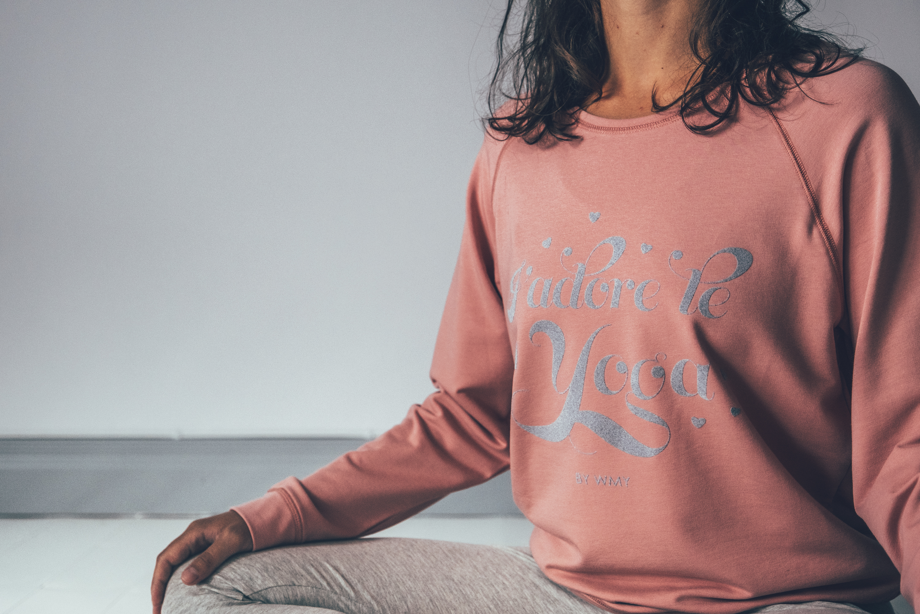 Model wearing a pink yogasweater with the letters I'adore Yoga in grey.