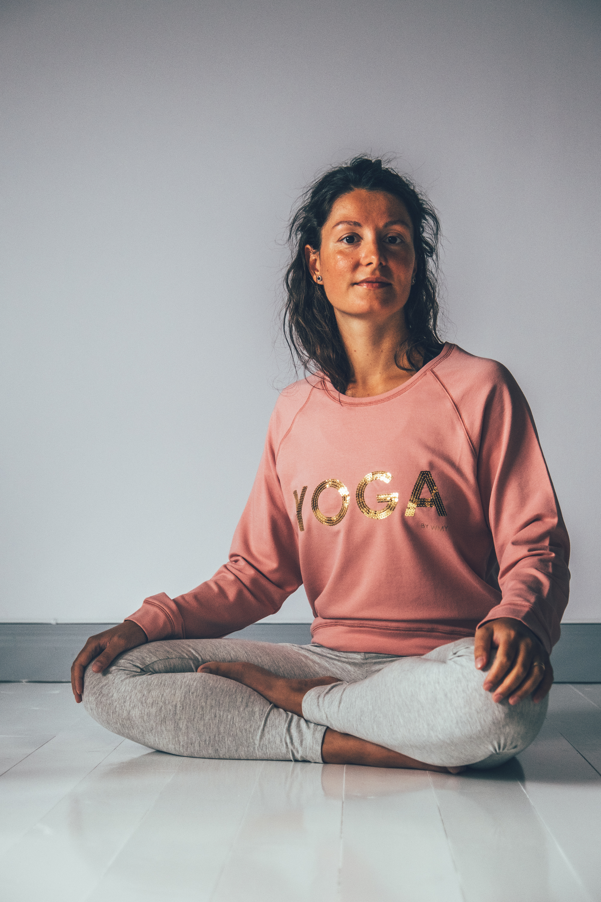 Model wearing a pink yogasweater with the letters YOGA in gold.