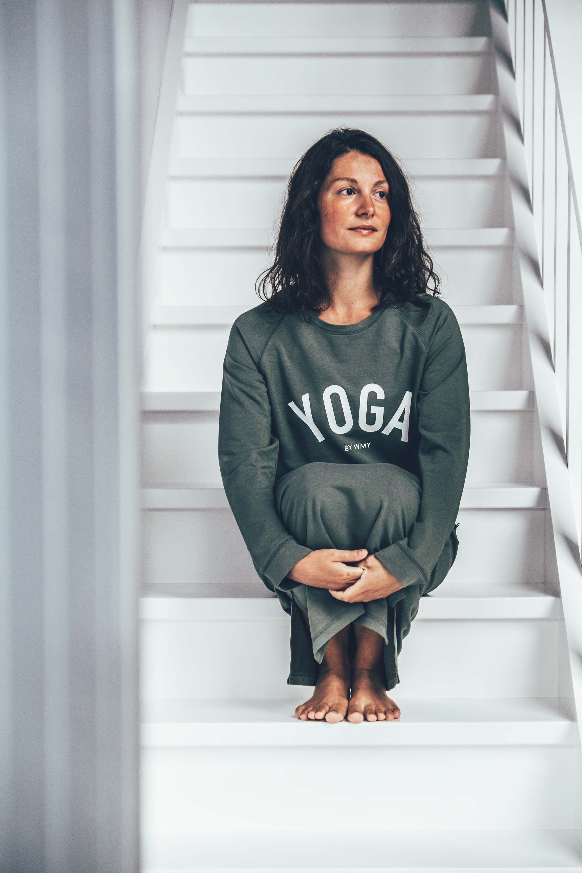 Model wearing a khaki green yogasweater with the letters YOGA in white.