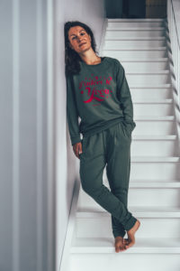Model wearing a khaki green yogasweater with the letters J'adore Yoga in hot pink.