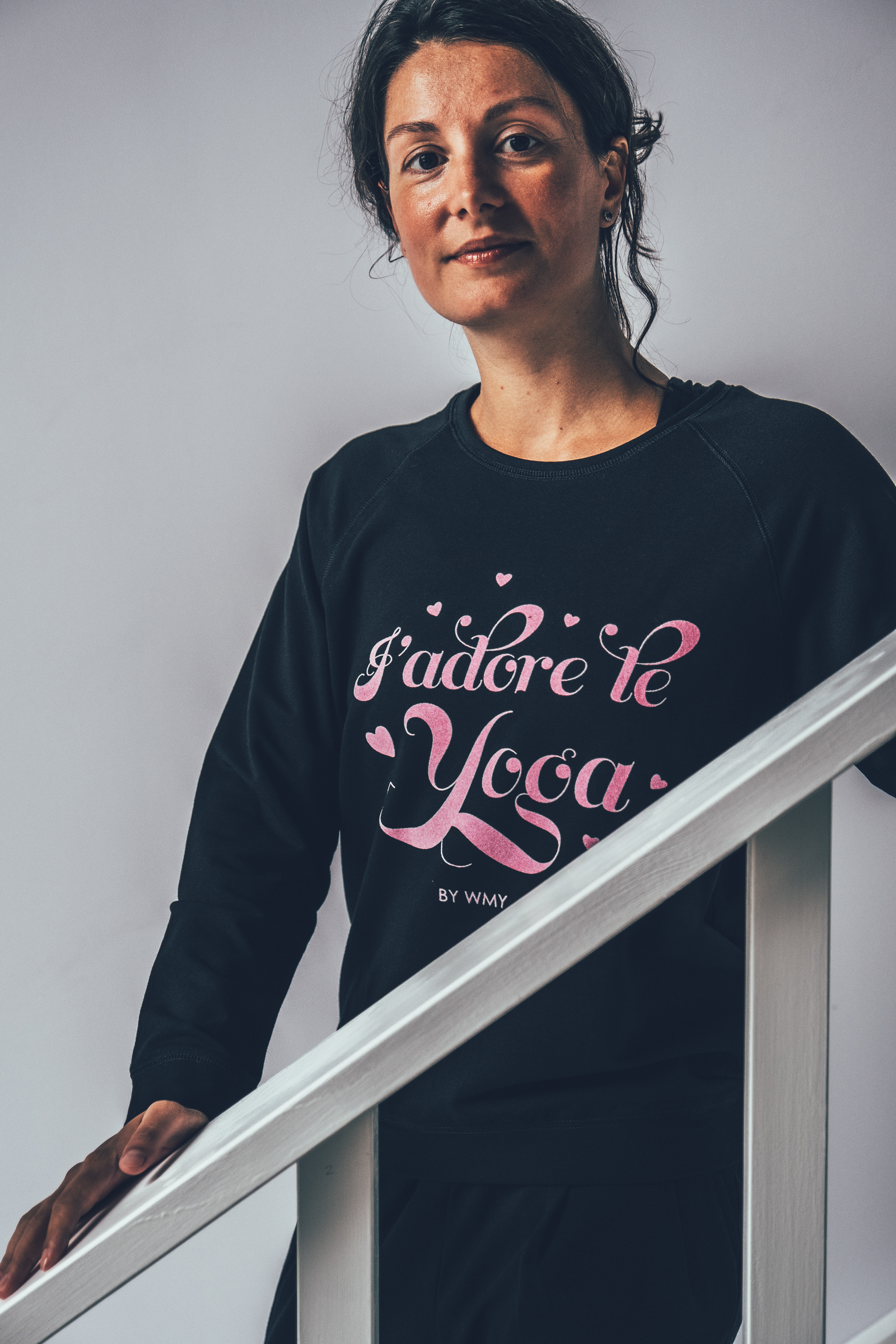 Model wearing a black yogasweater with the letters I'adore Yoga in pink.