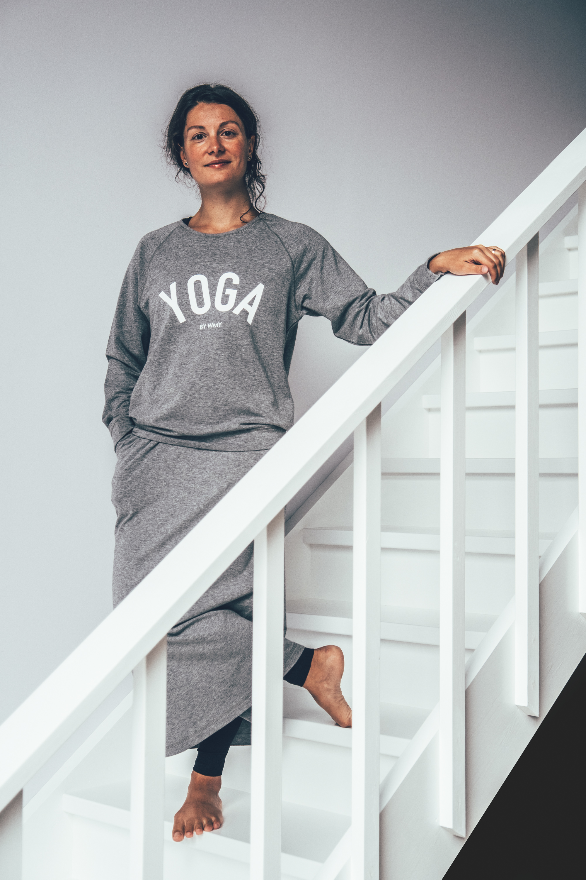 Model wearing a grey yogasweater with the letters YOGA in white.