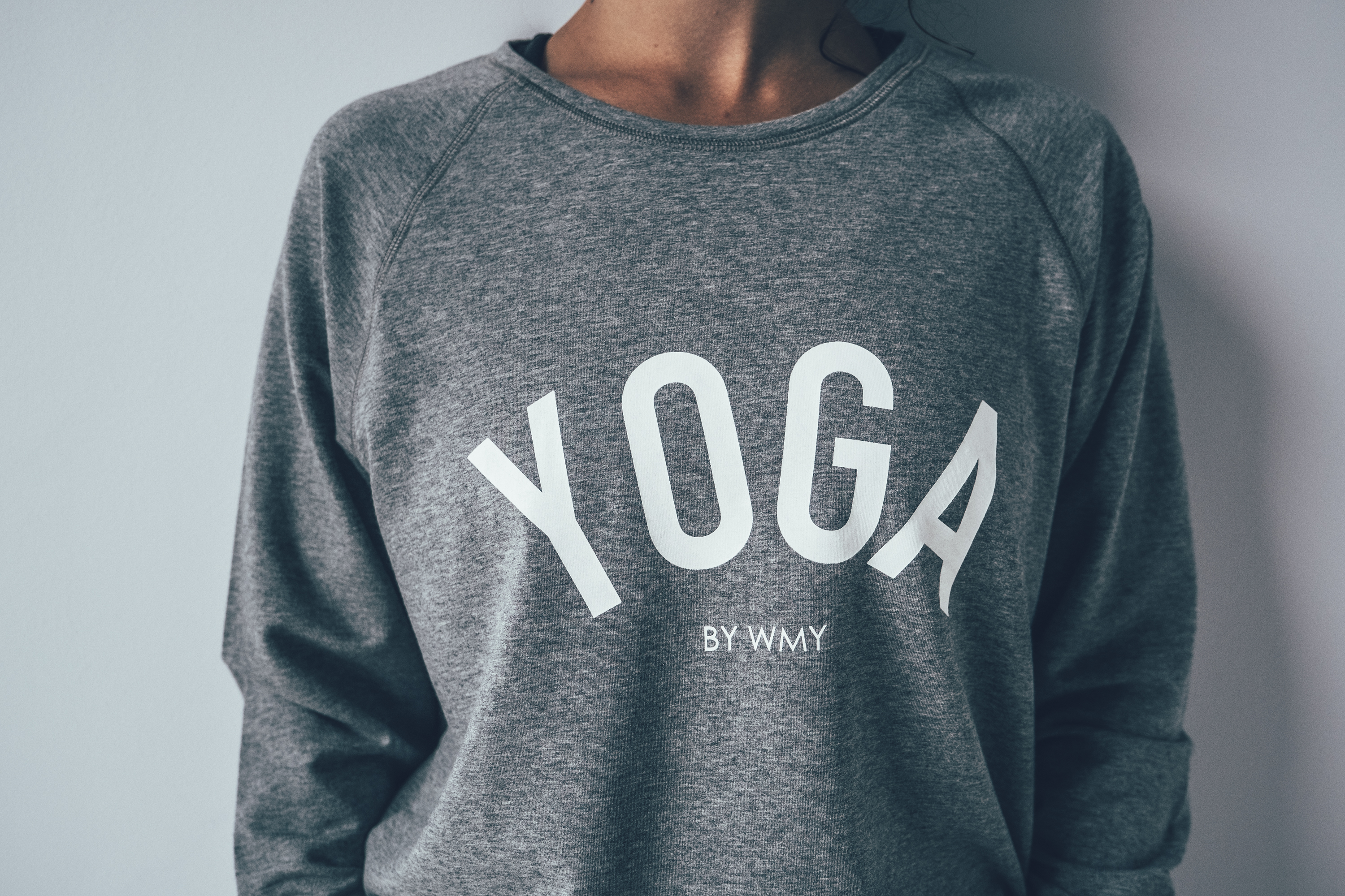 Model wearing a grey yogasweater with the letters YOGA in white.