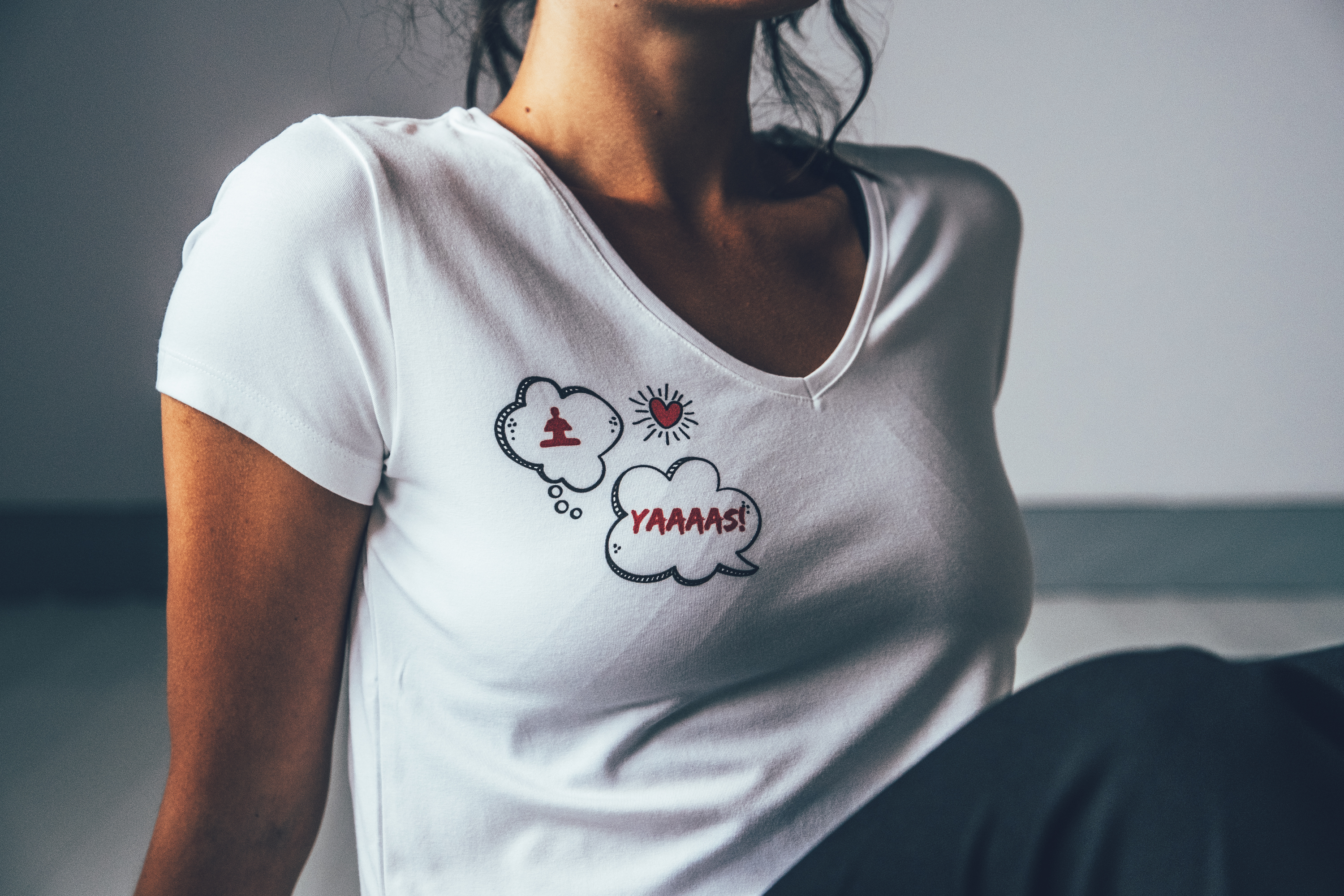 Model i vit t-shirt med yoga-tryck på höger bröst.