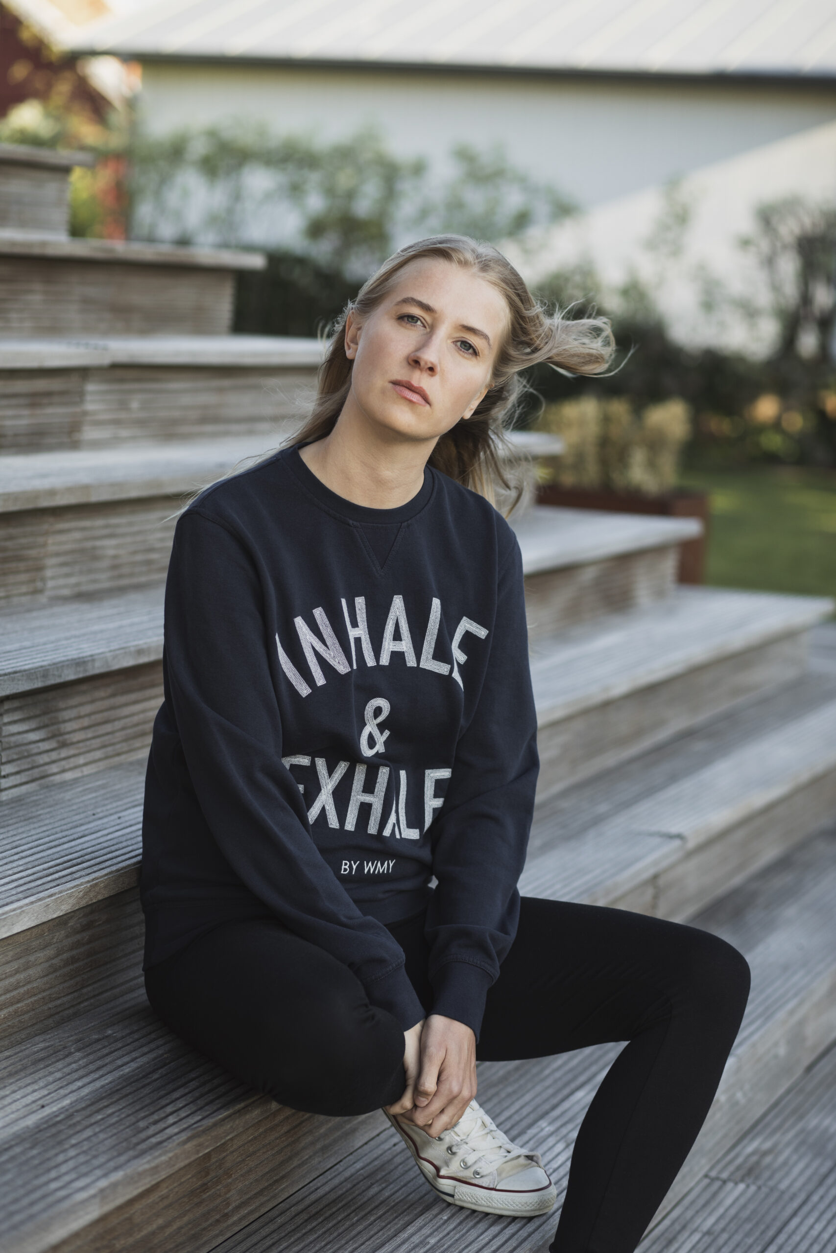 Model i yogatröja med Inhale & Exhale broderat på en sweatshirt i marinblått.