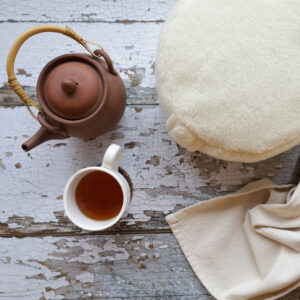 Merino medetationspuff, en filt, en kanna te och kopp.