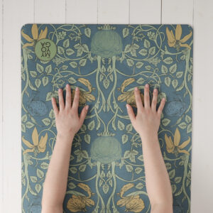 Händer vilandes på en art Nouveau yogamatta i blågrönt.