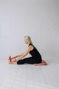Yogi sittandes på en liten meditationsmatta användandes ett yoga bälte.