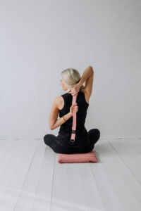 Yogi sittandes på en liten meditationsmatta användandes ett yoga bälte.