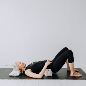 Yoga med nacken vilandes på en liten kudde och ett litet resebolster i svanken.