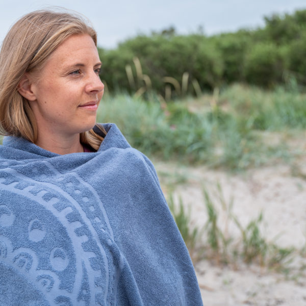Kvinna insvept i en stor blå strand, model handduk Hamsa