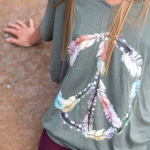 Girl wearing a khaki Peace tee top.